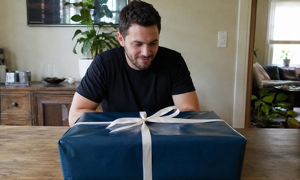 Mann sitzt vor Geschenkideen für Männer