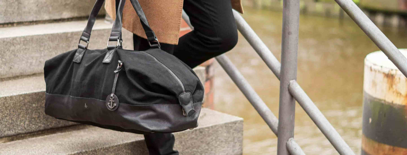 Mann mit Reisetasche aus Leder Modell Cajus in Dark Ash